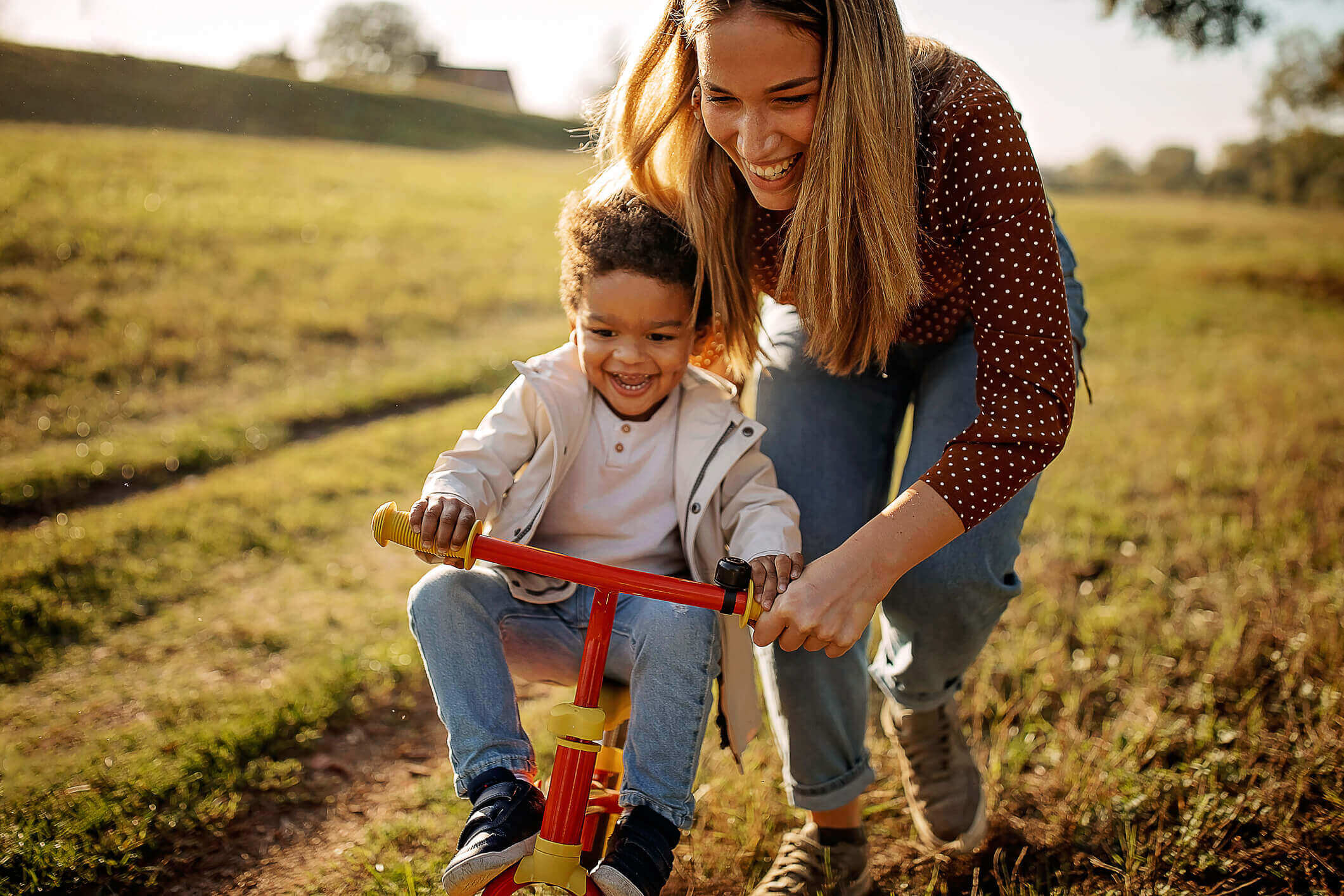 A woman teaching a little boy to ride a bike