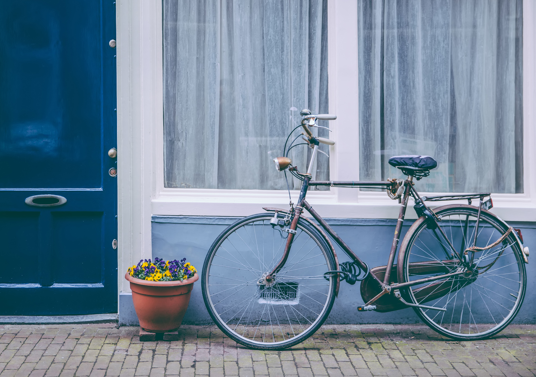 A bicycle leaning against the wall of a blue building