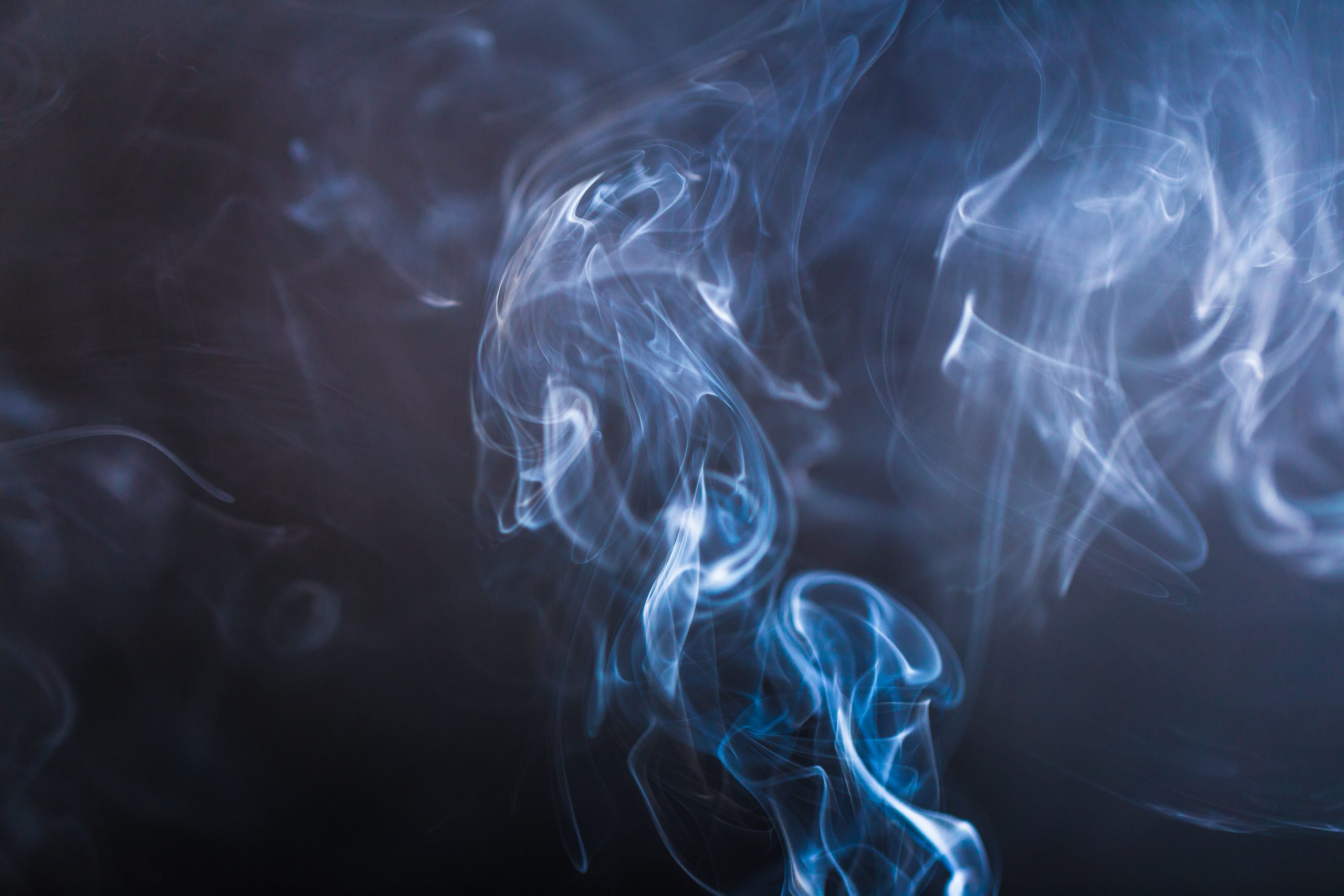 Blue swirling smoke abstract close up on black background