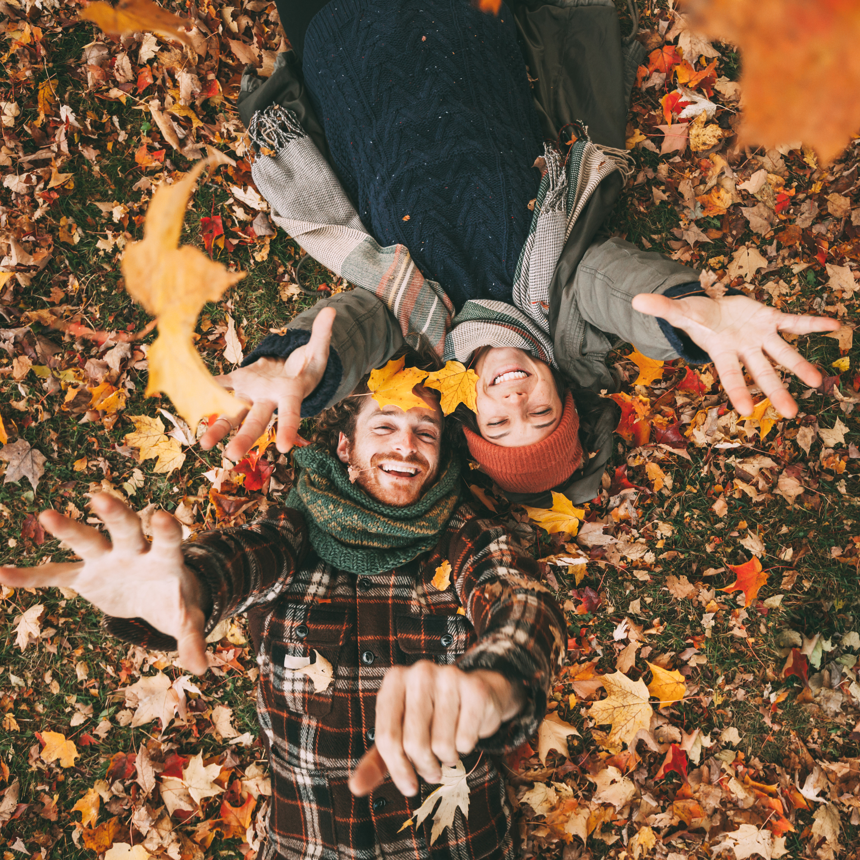 Cute young couple playing with autumn leaves