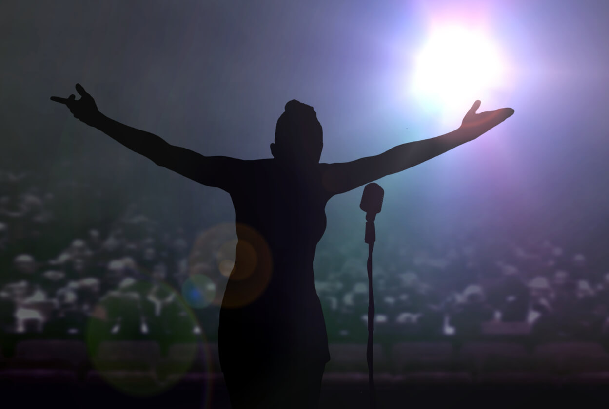A woman standing on stage with her arms spread