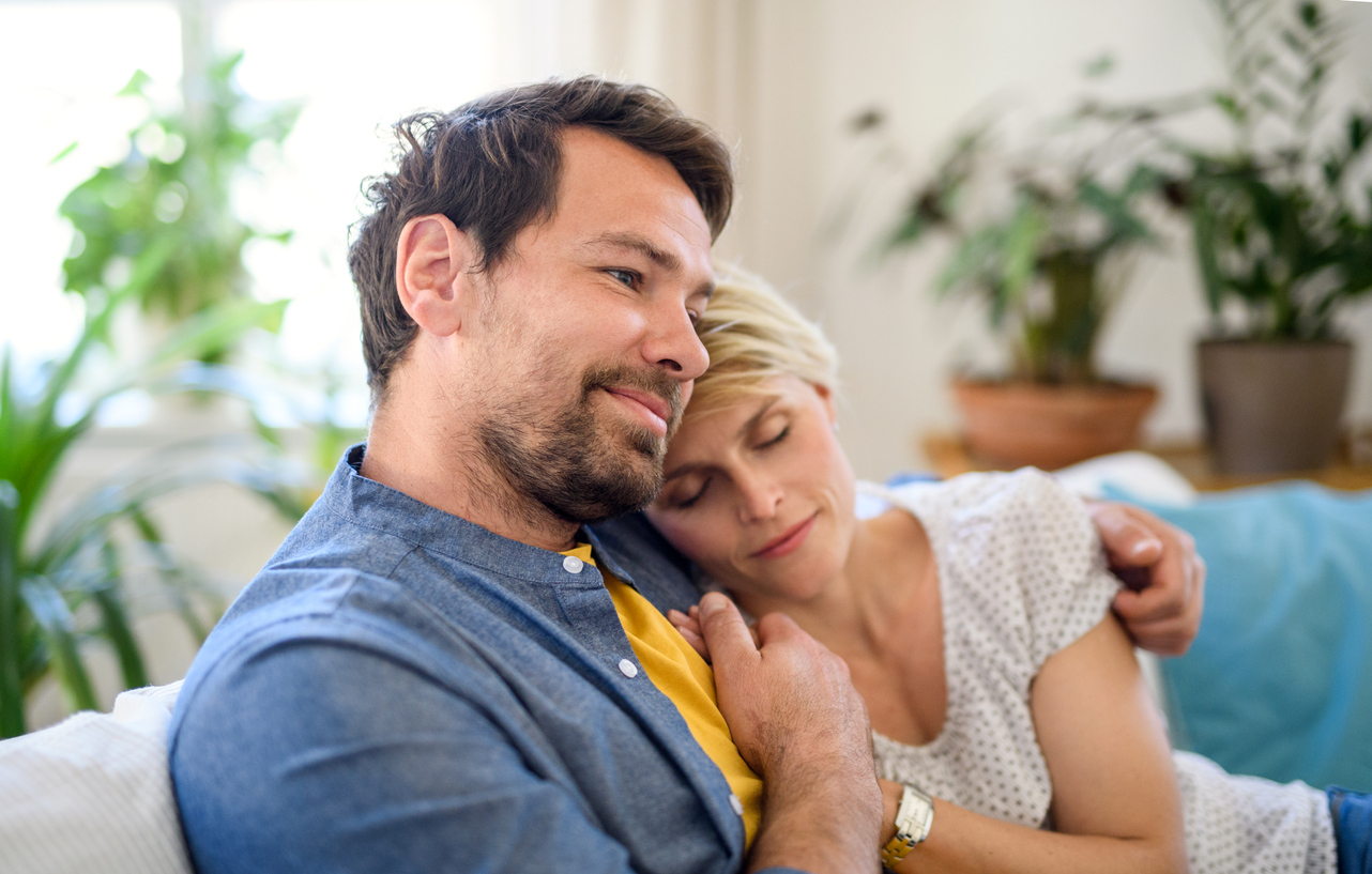 Happy couple in love sitting indoors at home hugging