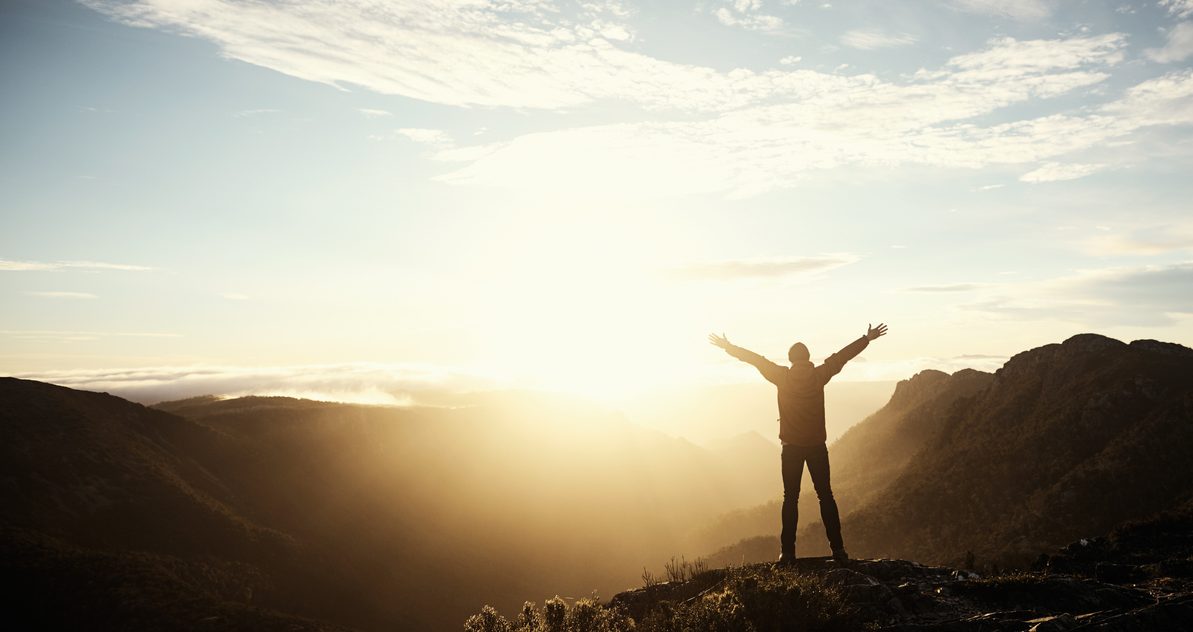 Shot of a young man embracing the morning sun while hiking in the mountains