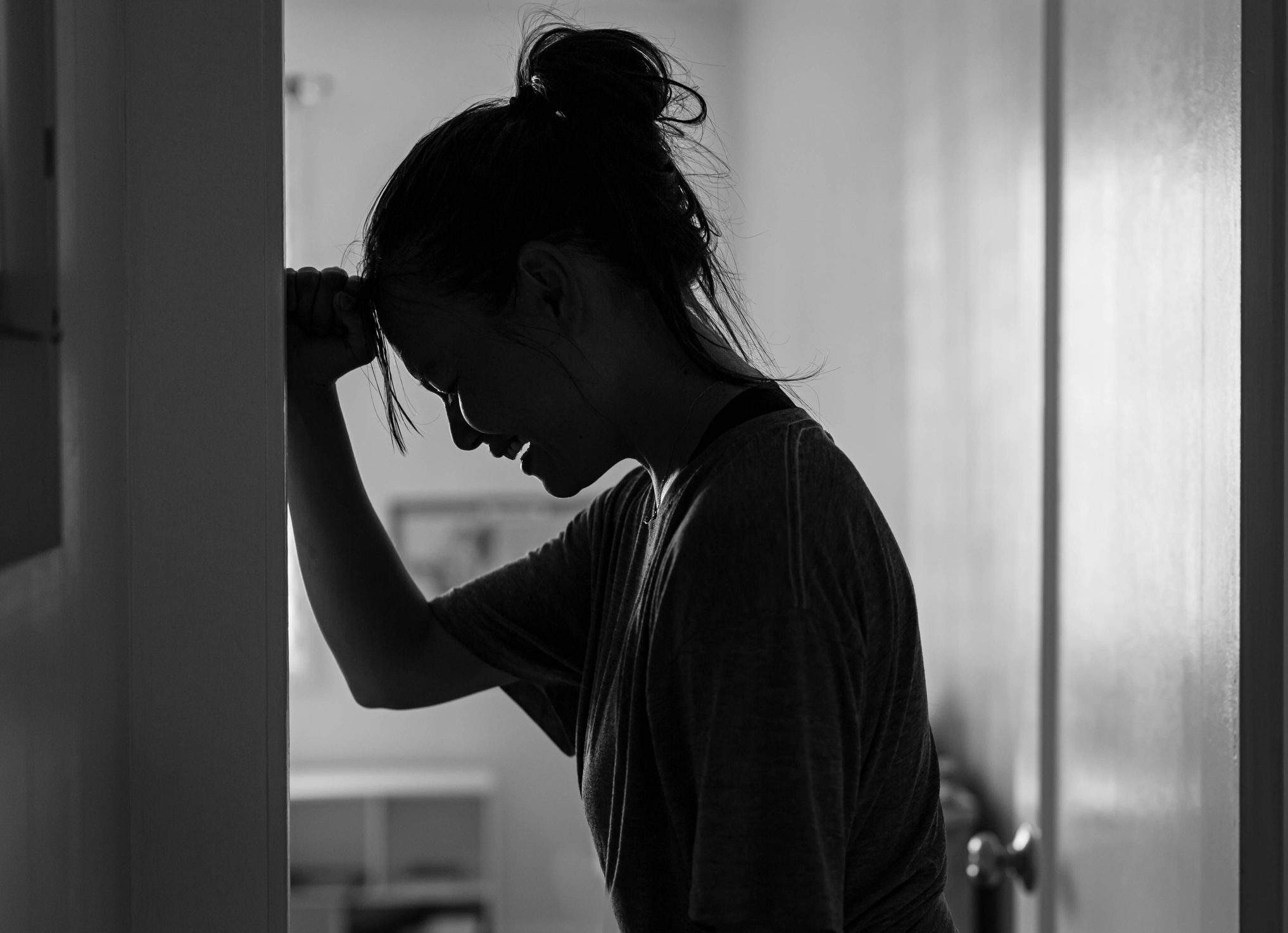A sad woman crying and depressed in her room at home alone.