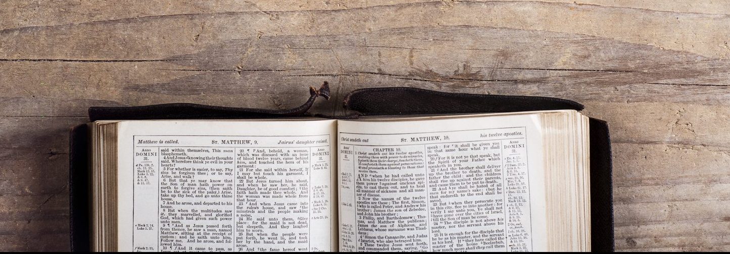 Opened bible on a wooden desk background