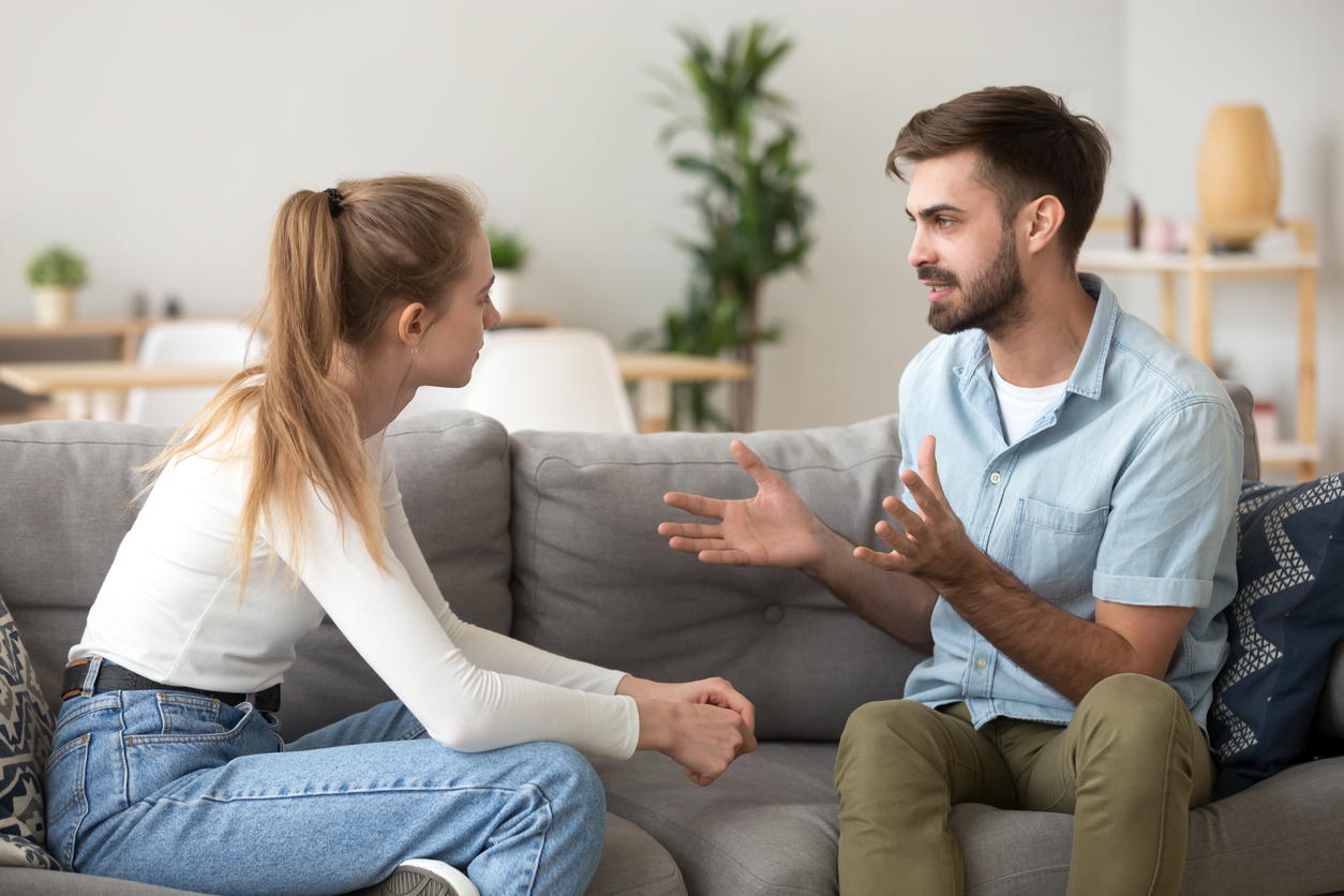 Serious young couple sitting together talking about relationships