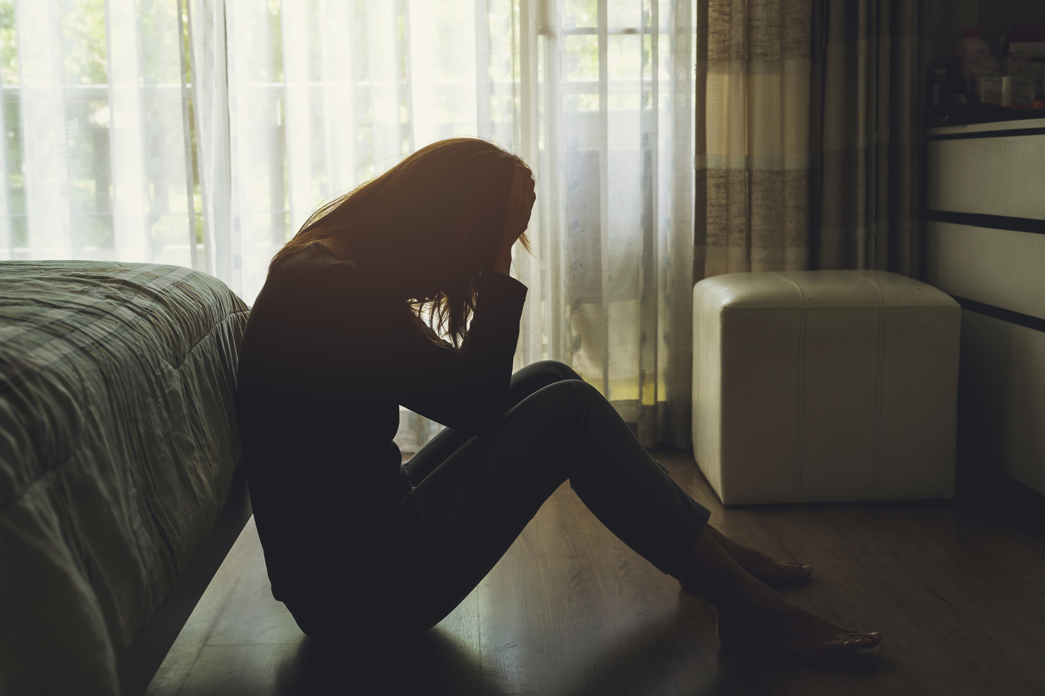 Depressed woman sitting in the dark bedroom
