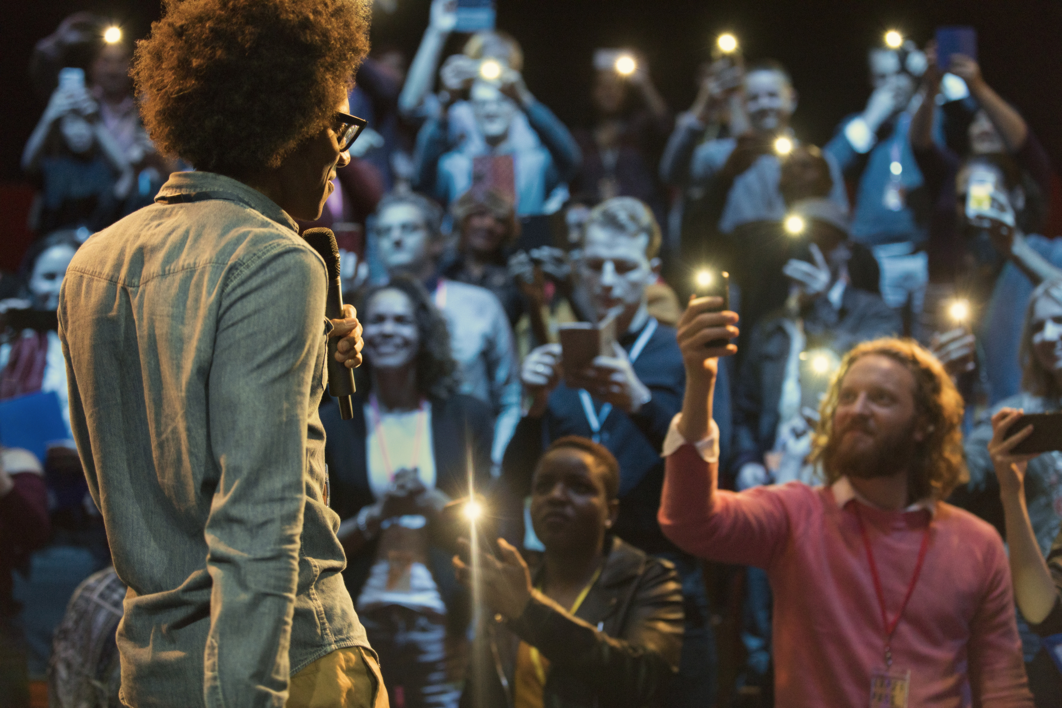Audience using smart phone flashlights watching speaker