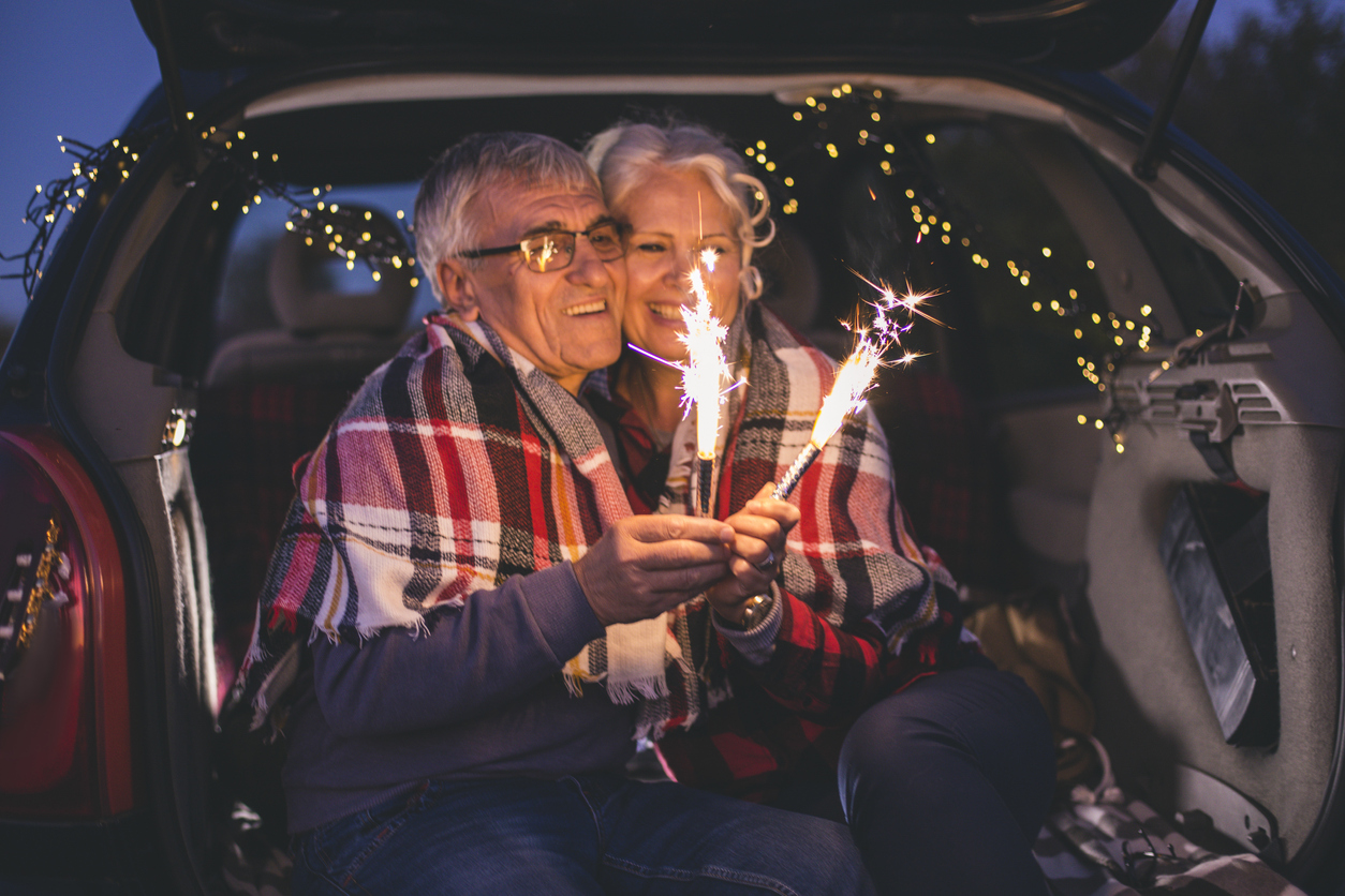 Couple of lovers kissing outdoors on a summer sunset, they hold spark sticks in their hands
