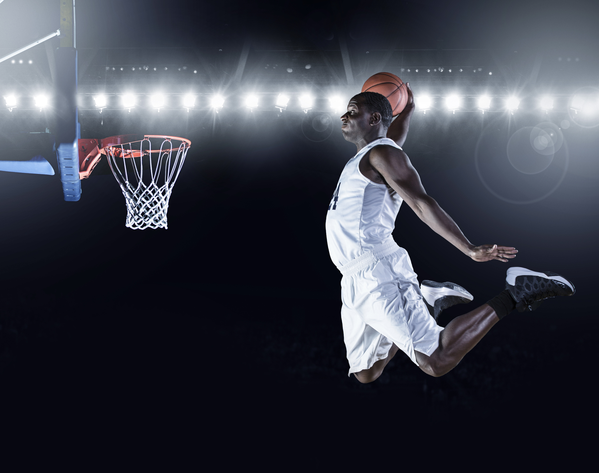 The side view of an african american basketball player scoring an amazing slam dunk in a professional basketball game