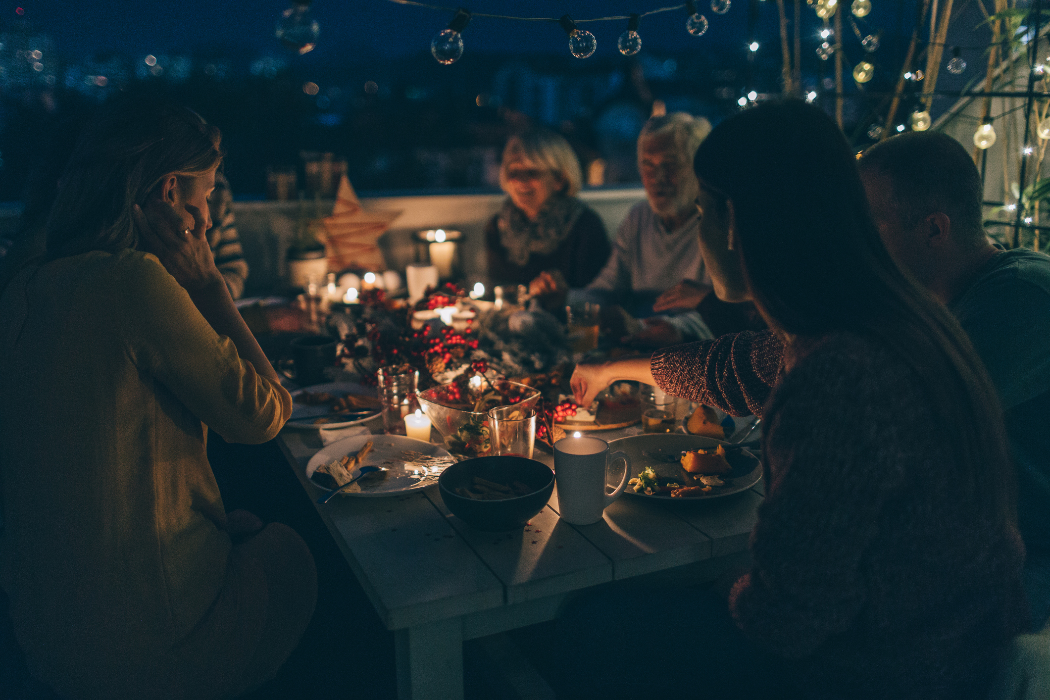 Photo of a multi-generation family having Thanksgiving dinner outdoors on their balcony