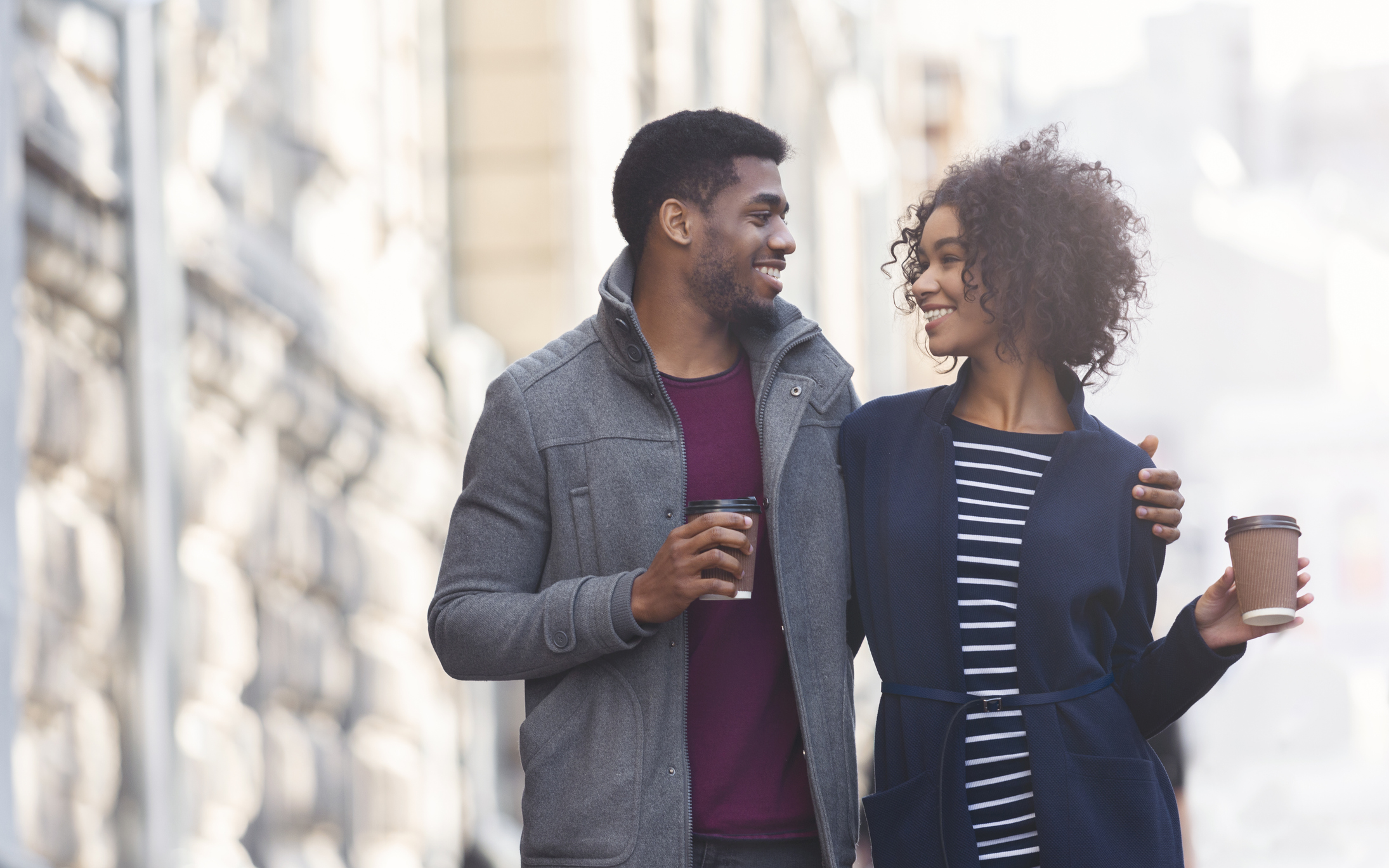 African american man and woman drinking coffee outdoors