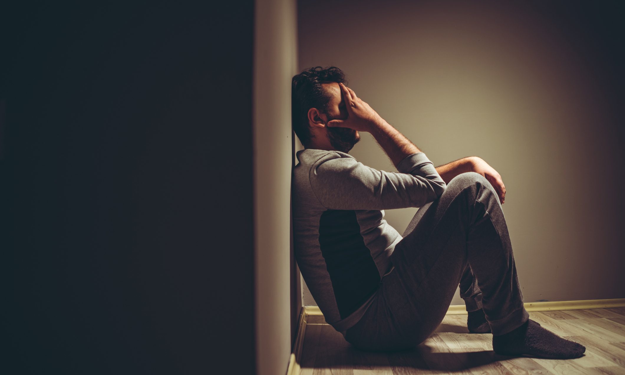 Young disappointed man sitting on floor.