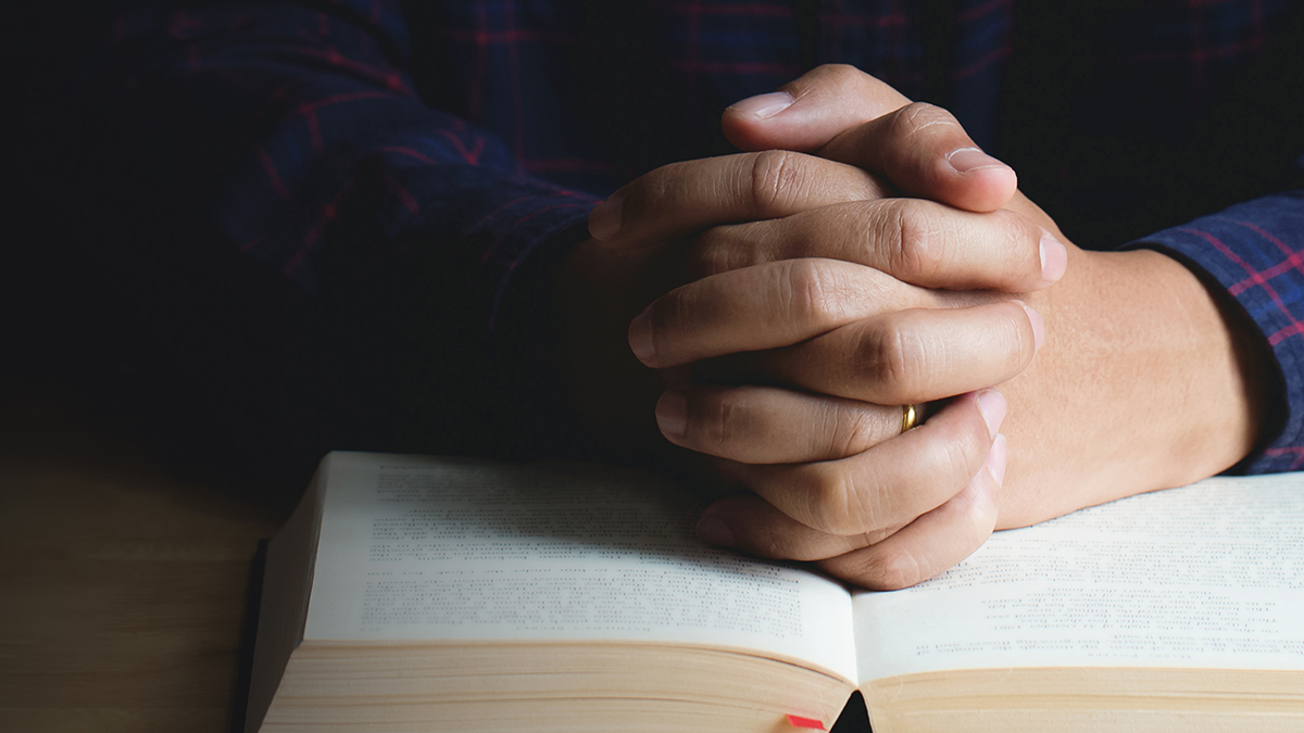Folded hands on bible