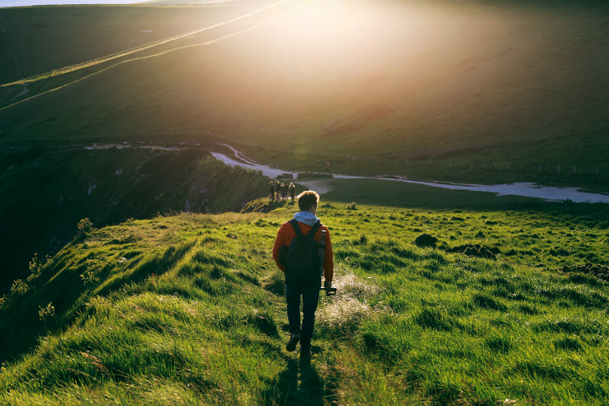 A man walking in the mountains with the setting sun in the background
