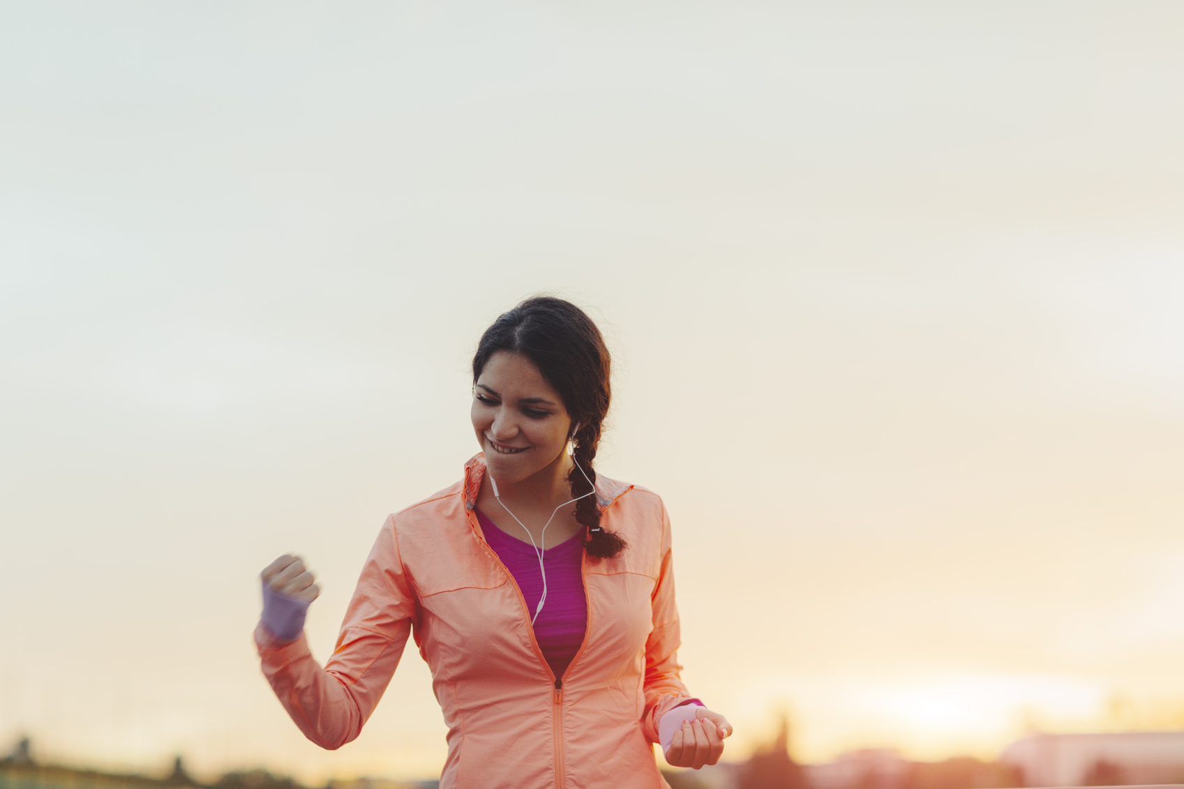 Female runner jogging in the city and finishing her training with her hand up in the air screaming with happiness