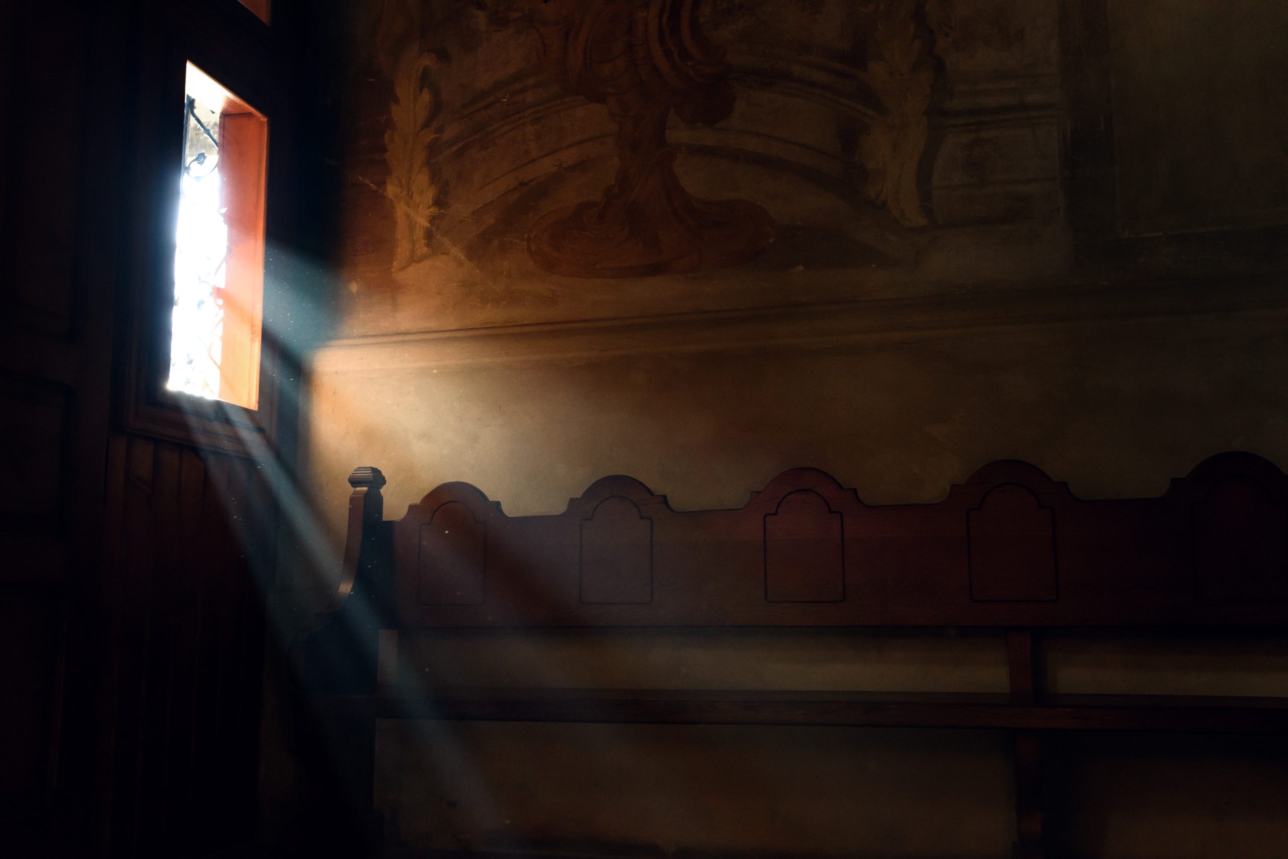 Light falling through window in old church on wooden bench, peaceful moment