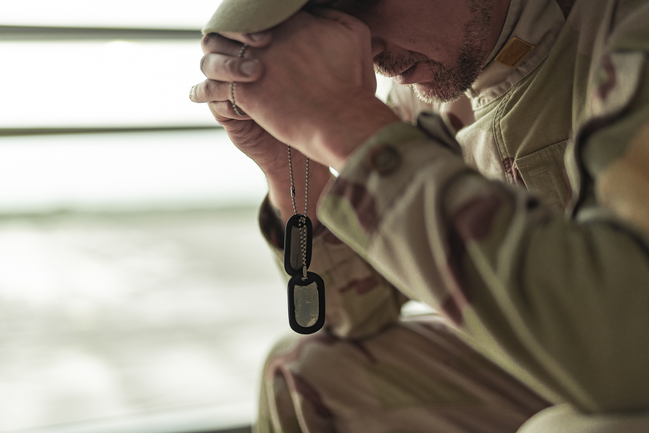 Close up of Caucasian adult man wearing military uniform and keeping his tags in hands