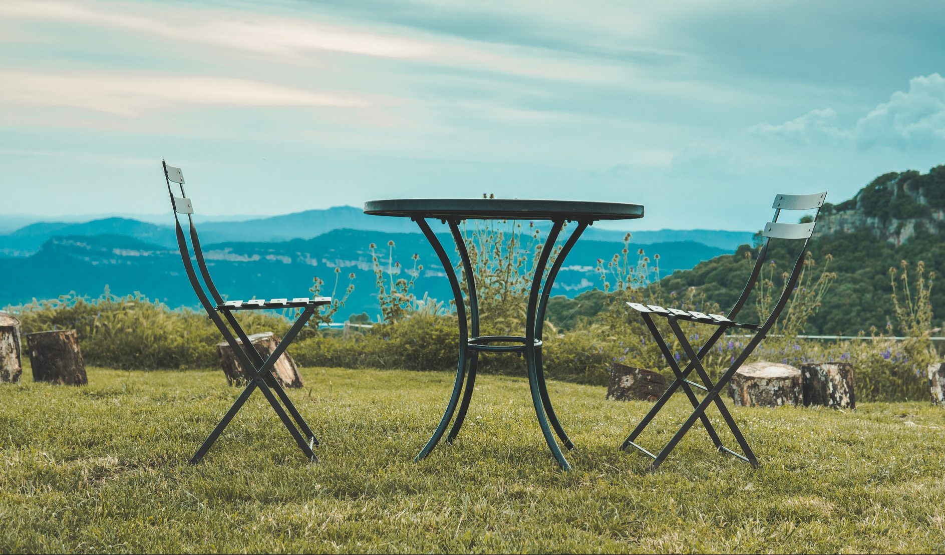 Two chairs facing each other and a table in the middle of nature