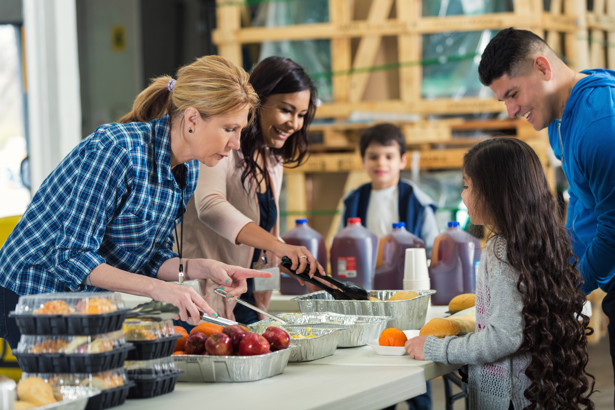 Two women serve family at soup kitchen