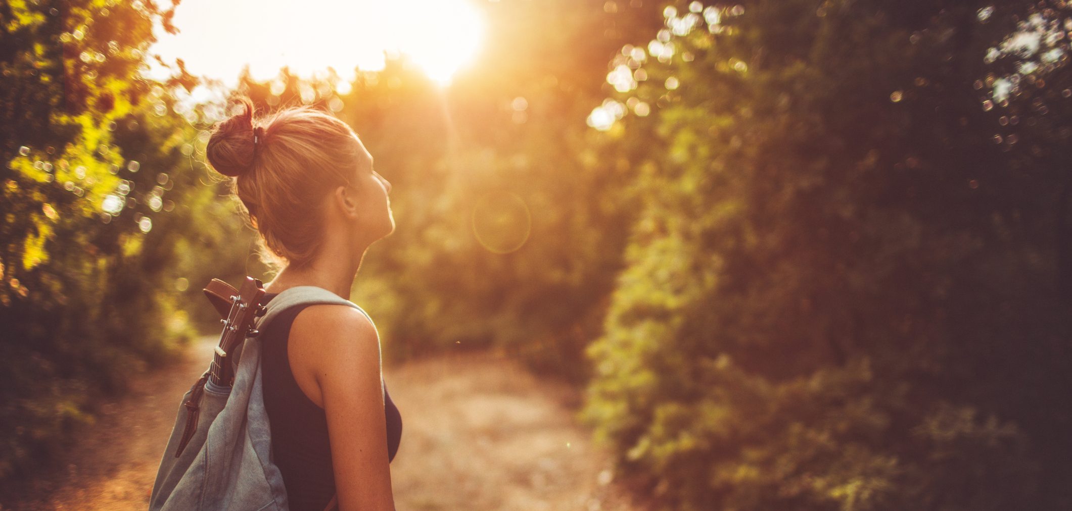 Photo of a young woman with a backpack wandering around in nature and relaxing