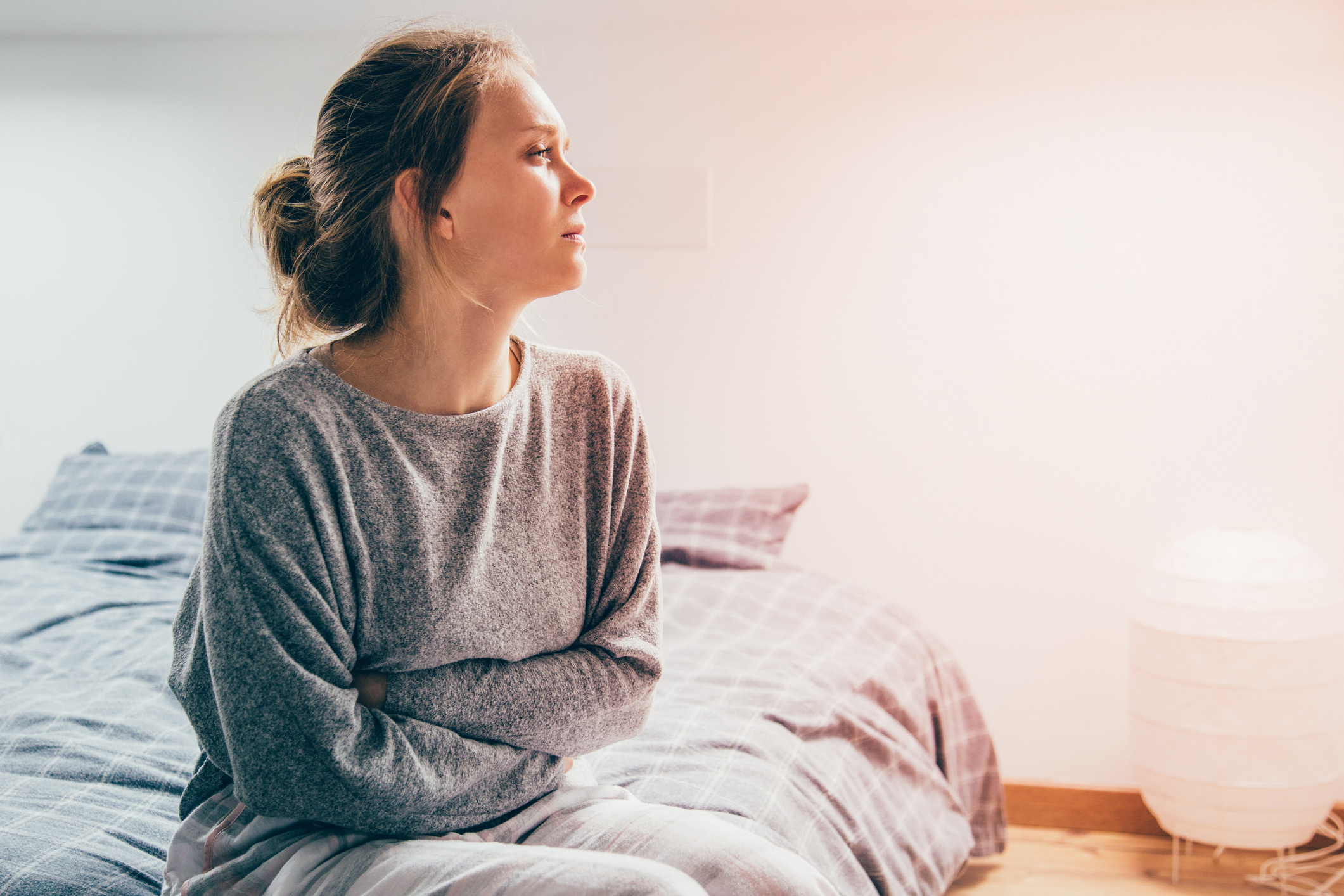 Woman with hands on stomach suffering from pain, looking aside