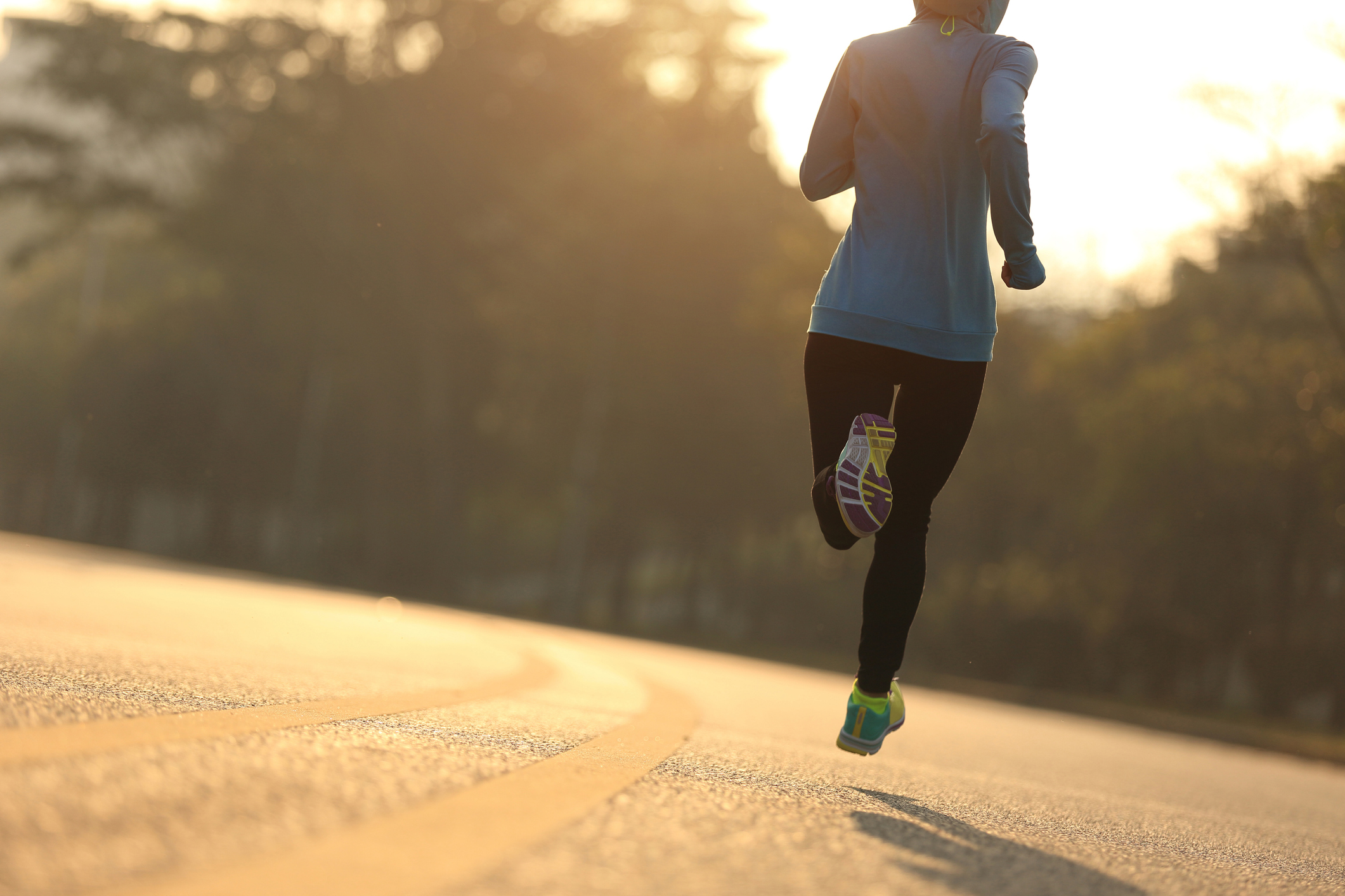 Young fitness woman runner running on sunrise road