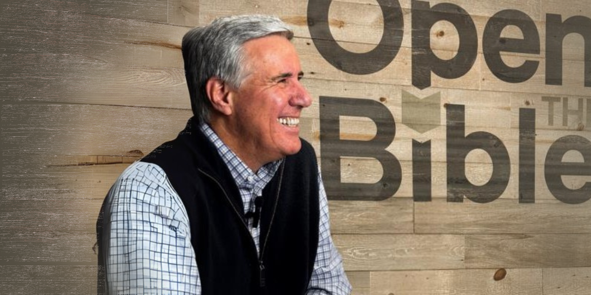 Pastor Colin smiling in front of a wooden background that says "Open the Bible"